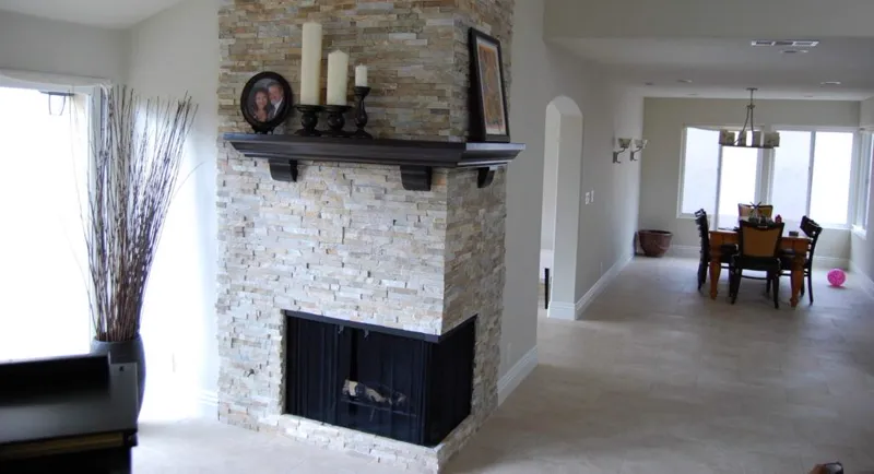 Fireplace with a stacked stone face and a dark wood mantel