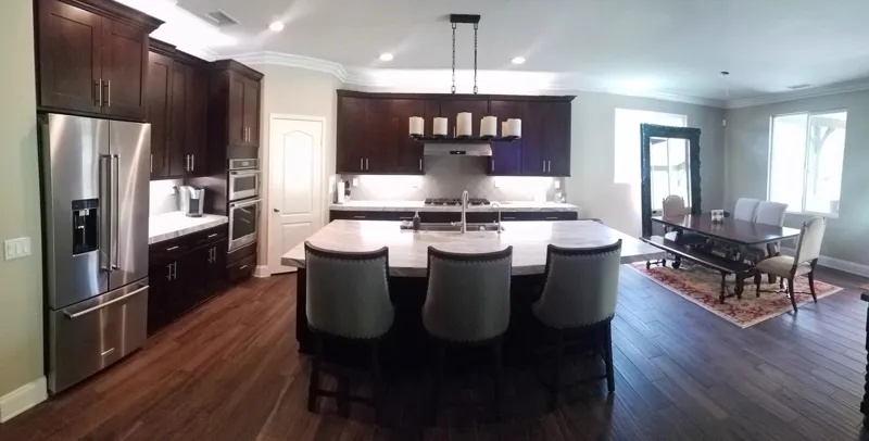 Kitchen with dark cabinets, a large island with seating and a dining area beyond