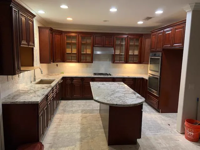 Cherry cabinet kitchen with glass doors, granite counters and an oval island