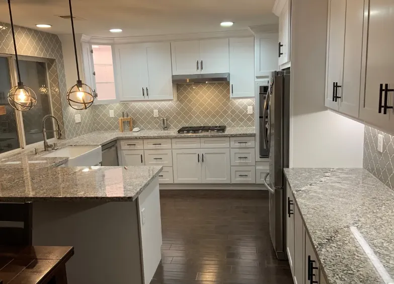 White shaker kitchen with granite counters, an arabesque tile backsplash and pendant lights