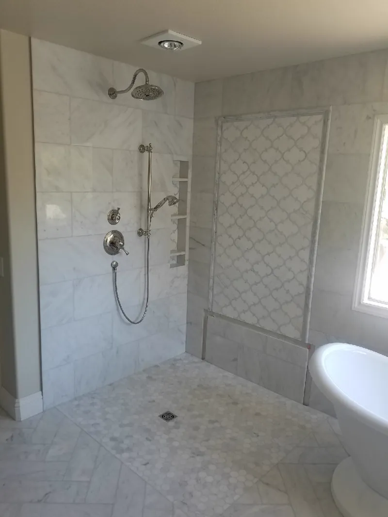 Tiled walk in shower with a rain head and a marble look accent panel