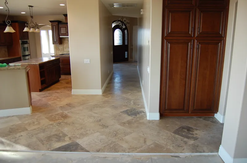 Travertine tile floor running from the kitchen into the front hall